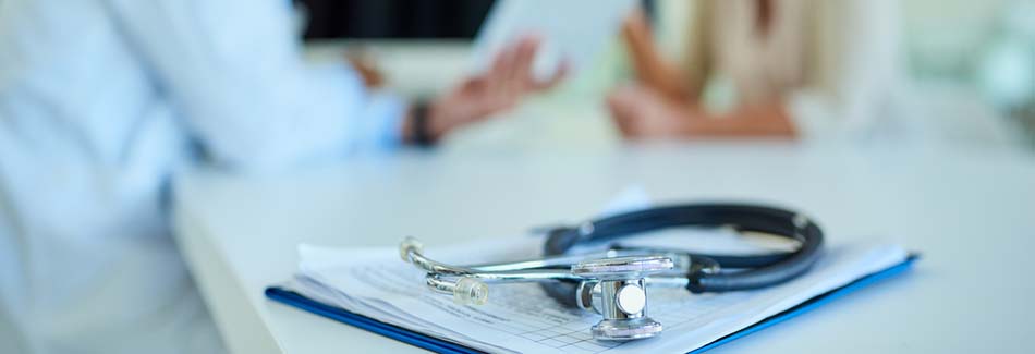 A Baptist doctor and patient discuss health insurance networks with paperwork